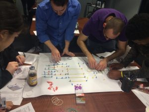 The engineering group uses push pins and rubber bands to represent the column and beam layout for the building.